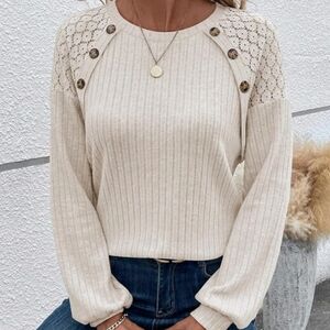 Women's lightweight sweater top with lace shoulders and button detail.